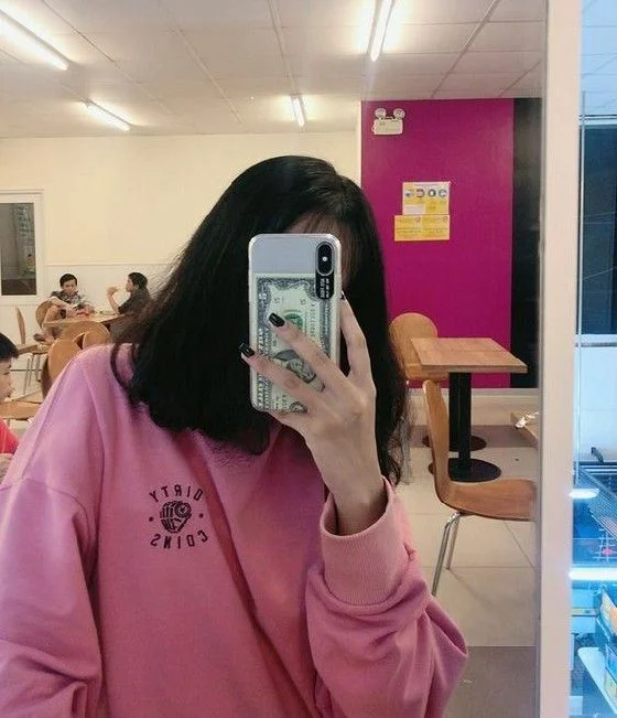 ảnh gái che mặt bằng điện thoại mặc áo hoodie hồng trong quán cà phê